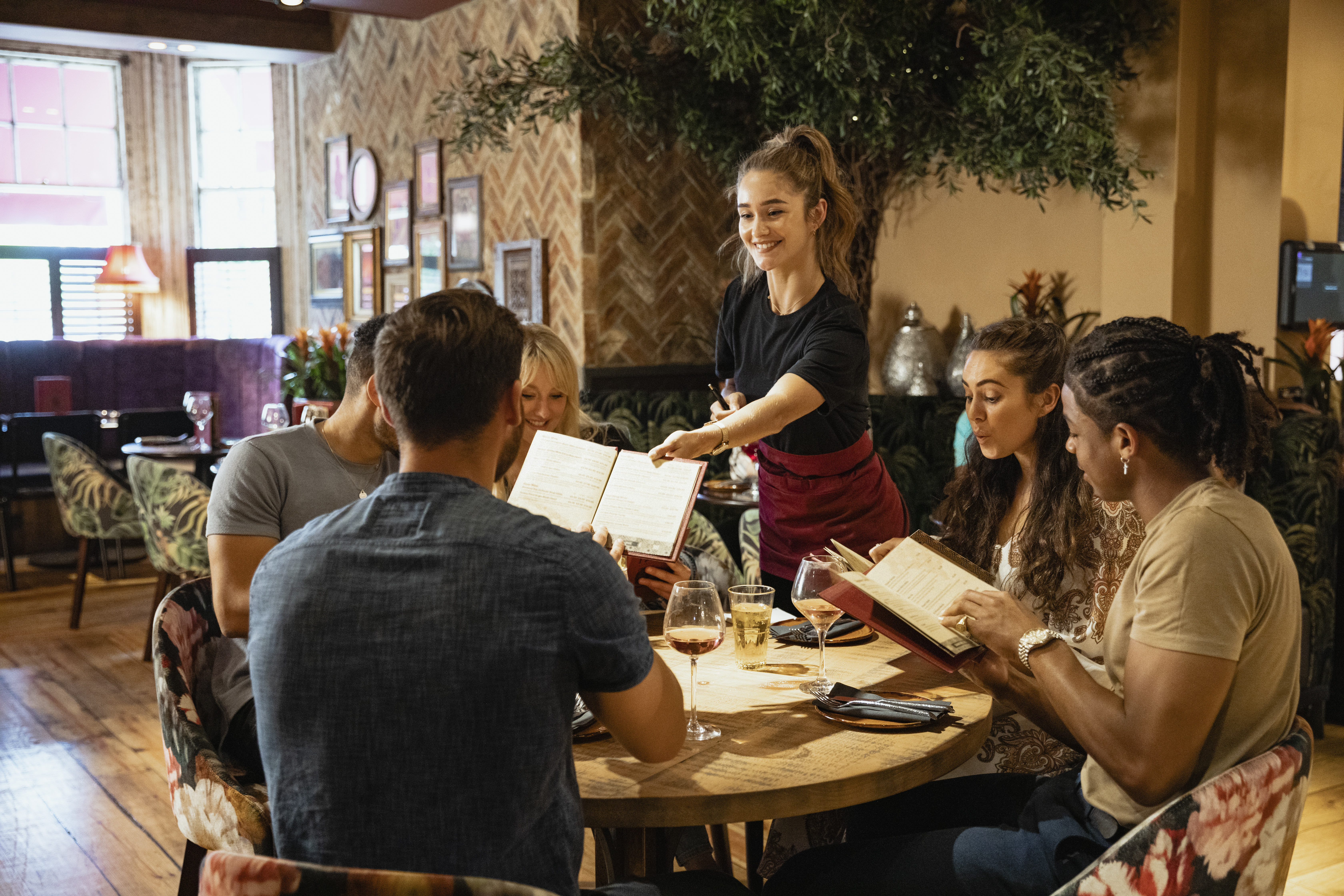 A waitress gives the menu to customers in a restaurant