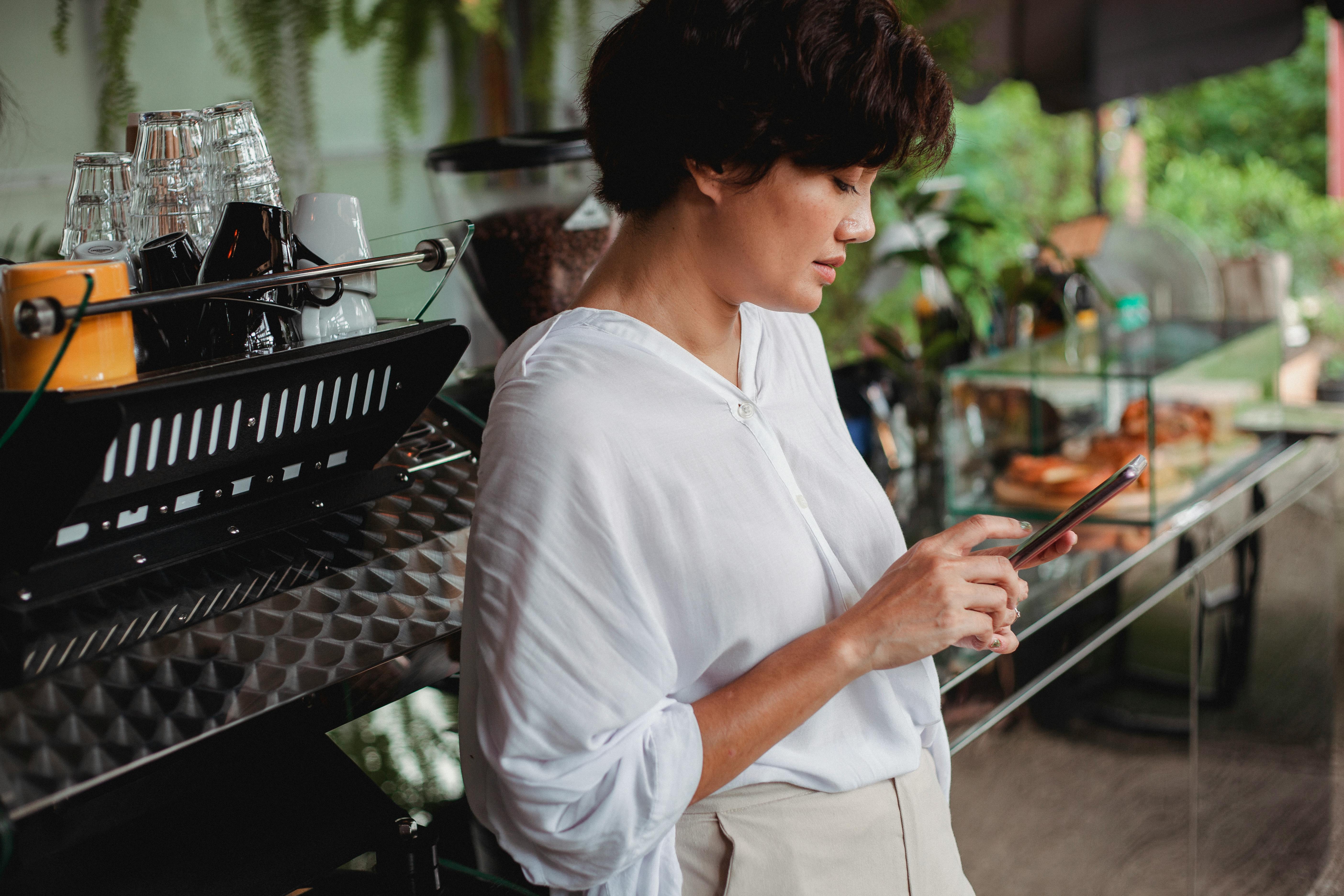 Frau arbeitet in einem Café mit ihrem Handy